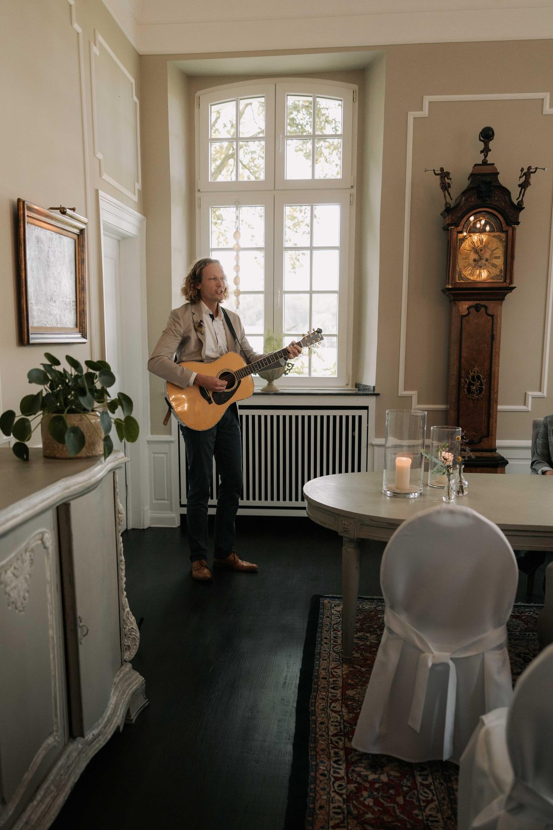 Tobi Sonic mit Gitarre in einem Saal mit Kerzen und Standuhr